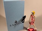 a figurine of a woman in a pink dress next to a blue box