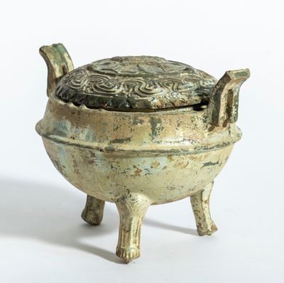 un petit pot en bronze muni d'un couvercle et posé sur un socle
