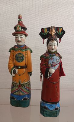 three ceramic figurines of asian people on display in a glass case