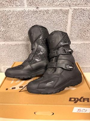 the pair of black motorcycle boots are sitting on a cardboard box