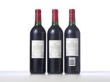 three bottles of red wine sit side by side on a table