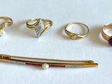 cinq bagues, une broche, une épingle et une épingle-broche posées sur un fond blanc