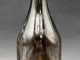 a glass bottle with a small amount of liquid inside of it