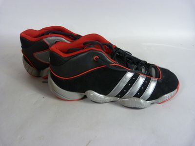 adidas shoes with red and black stripes are on a white surface