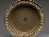 une assiette ancienne en bronze, ornée d'un motif décoratif sur le bord