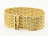 gros plan d'un bracelet en or sur fond blanc