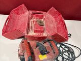 Deux boîtiers rouges, munis de fils et d'un cordon, sont posés sur une table