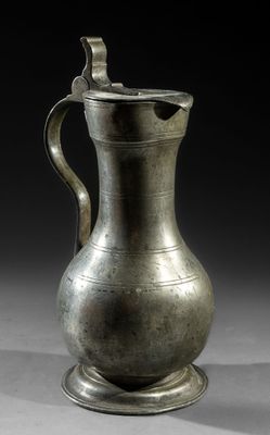an old silver pitcher with a handle on a stand