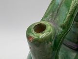 a green vase that has a hole in it