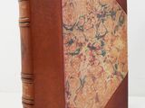 an old book with a brown leather cover and a floral design