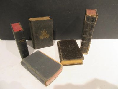 Plusieurs vieux livres sont posés les uns à côté des autres sur une surface blanche.