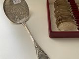 a silver spoon with coins in it next to a box of coins