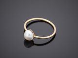 a gold ring with a white pearl on a black surface