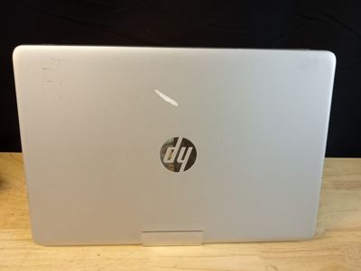 Un ordinateur portable HP posé sur une table en bois, sur fond noir