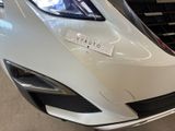 the front end of a white car with a sticker on it ' s bumper