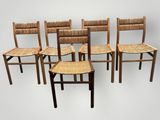 quatre chaises en bois avec des assises tressées, alignées sur un fond blanc