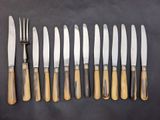 a set of six knives and a fork on a table