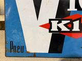 a blue and white sign with a red v for kt logo on it