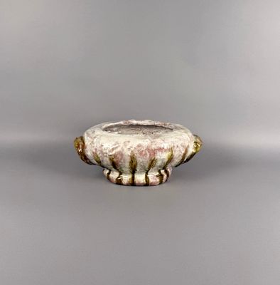 un petit vase blanc avec un socle marron posé sur une surface grise