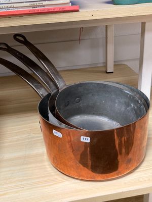 des casseroles et des poêles posées sur une étagère en bois dans une pièce