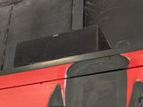 graffiti on the side of a red bus with a camera attached to it