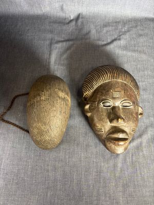 une paire de masques africains et une boule posés sur un tissu blanc