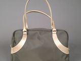 the large grey and gold bag is sitting on a gray surface