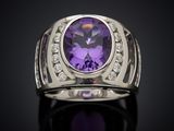 a close up of a ring with a purple stone surrounded by diamonds