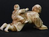 two figurines of men wrestling each other on a black surface