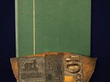 an old book sitting on top of a table next to a green book