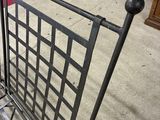 a metal bench sitting on the sidewalk next to a red rug