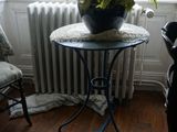 une petite table sur laquelle se trouve une plante en pot, devant une fenêtre