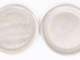 deux assiettes blanches avec leurs couvercles sont posées sur une surface blanche