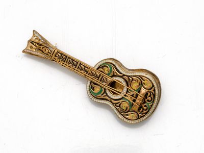 une broche en forme de guitare dorée sur un fond blanc