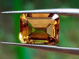 un gros plan d'un diamant jaune tenu par une paire de pinces