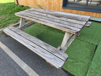 a wooden picnic table sitting in front of a building