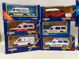 six toy ambulances in boxes on a table with a white background