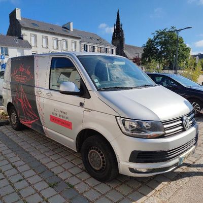 La camionnette est garée sur le bord de la route, devant un immeuble.