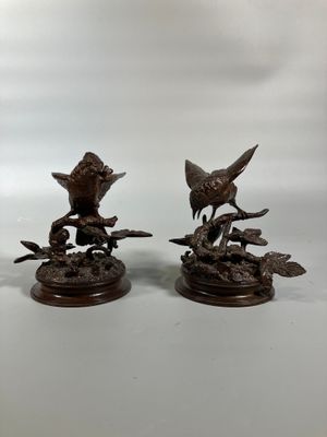 two bronze figurines of birds perched on a tree branch