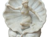 statue d'une femme assise sur un coquillage, tenant un poisson à la main
