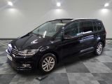 La Volkswagen Touran noire est garée sur un sol en carrelage à damier.