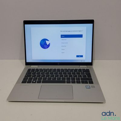 un ordinateur portable ouvert posé sur une table blanche