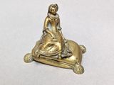 brass figurine of a woman sitting on a pillow with a cat