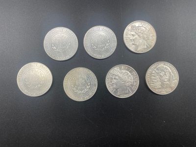 six pièces d'argent de tailles et de formes différentes sur un fond noir