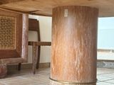a wooden table with a wooden base and a wooden chair in the background