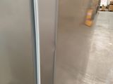a silver refrigerator in a warehouse with boxes in the background