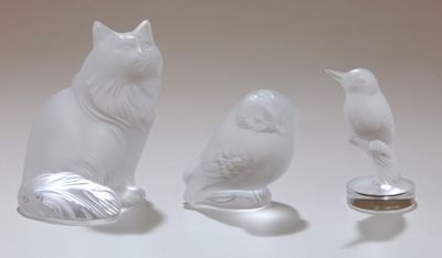 trois figurines représentant des chats et un oiseau posées sur une table