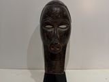 an image of a wooden mask sitting on top of a white table
