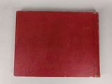 an old red book sitting on top of a white table
