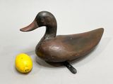 a small wooden duck next to a lemon on a table